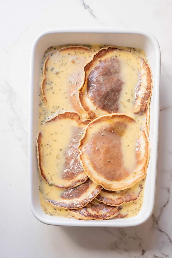 Sliced beef covered in creamy sauce in a white baking dish on a marble surface&mdash;an irresistible breakfast casserole recipe.