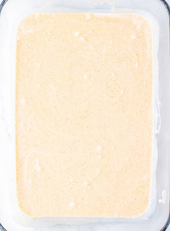 A rectangular dish filled with smooth, creamy, light orange batter or mixture, perfect for trying out a viral dumpling bake inspired by trending TikTok recipes.