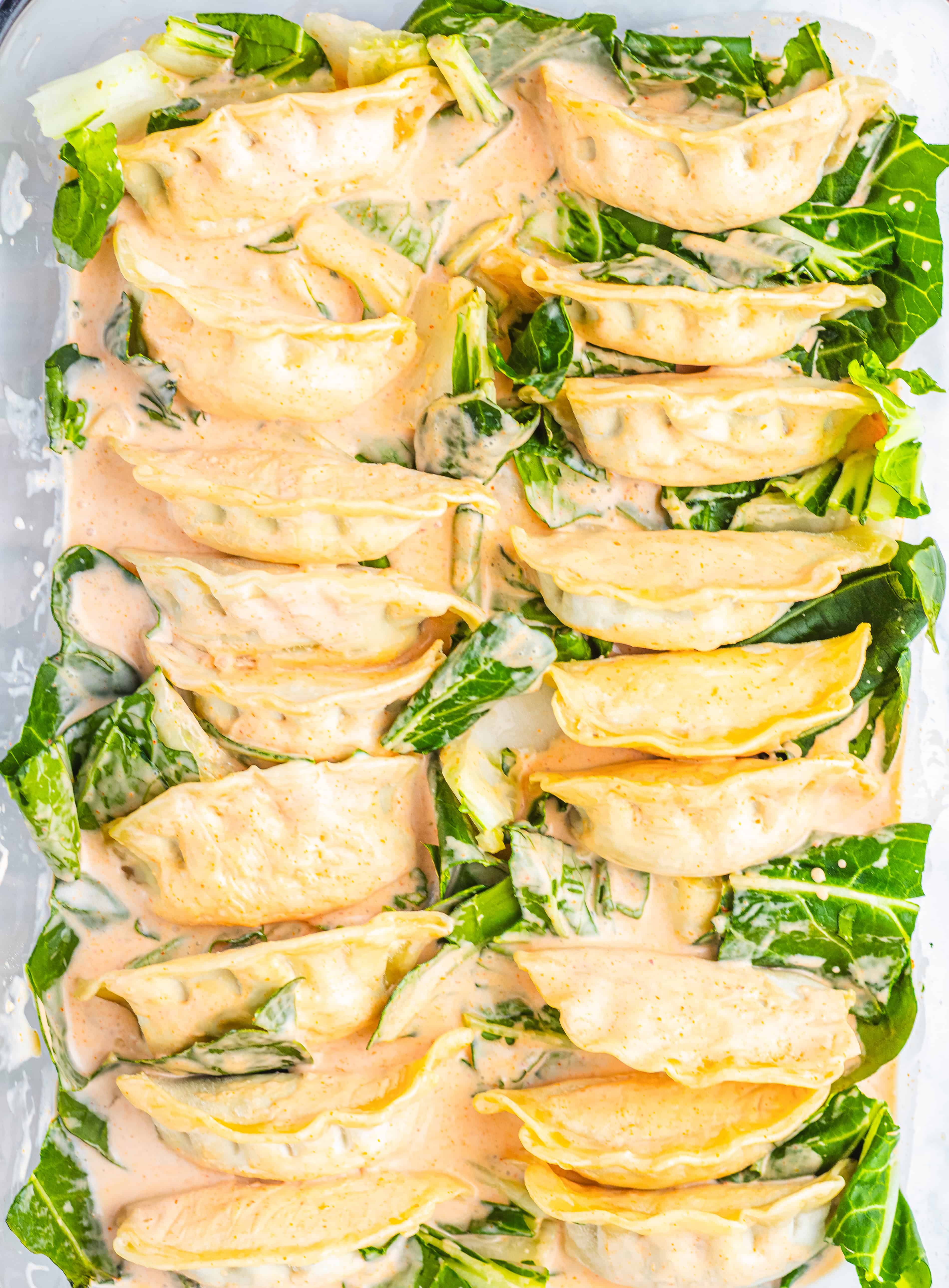 A baking dish filled with dumplings and leafy greens, this creamy dumpling bake is ready to be cooked—no wonder it's gone viral on TikTok!.