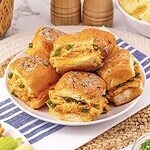 A plate of Easy Chicken Sliders filled with shredded chicken and green onions is served on a blue-striped cloth.