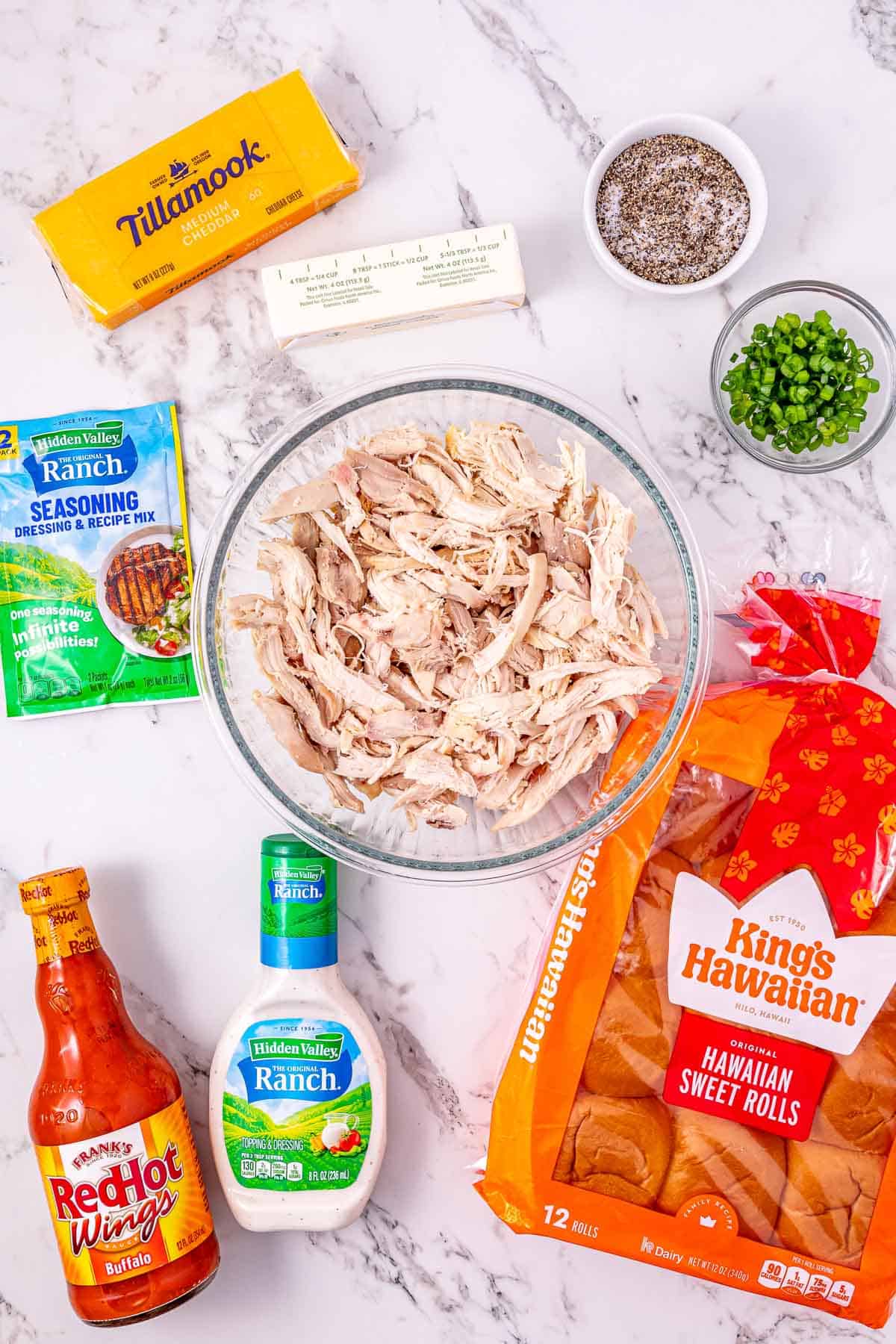 Ingredients for Buffalo Chicken Sliders, including tender chicken, cheese, rolls, seasonings, sauces, and fresh green onions. These Easy Chicken Sliders are perfect for game day or a quick weeknight meal.