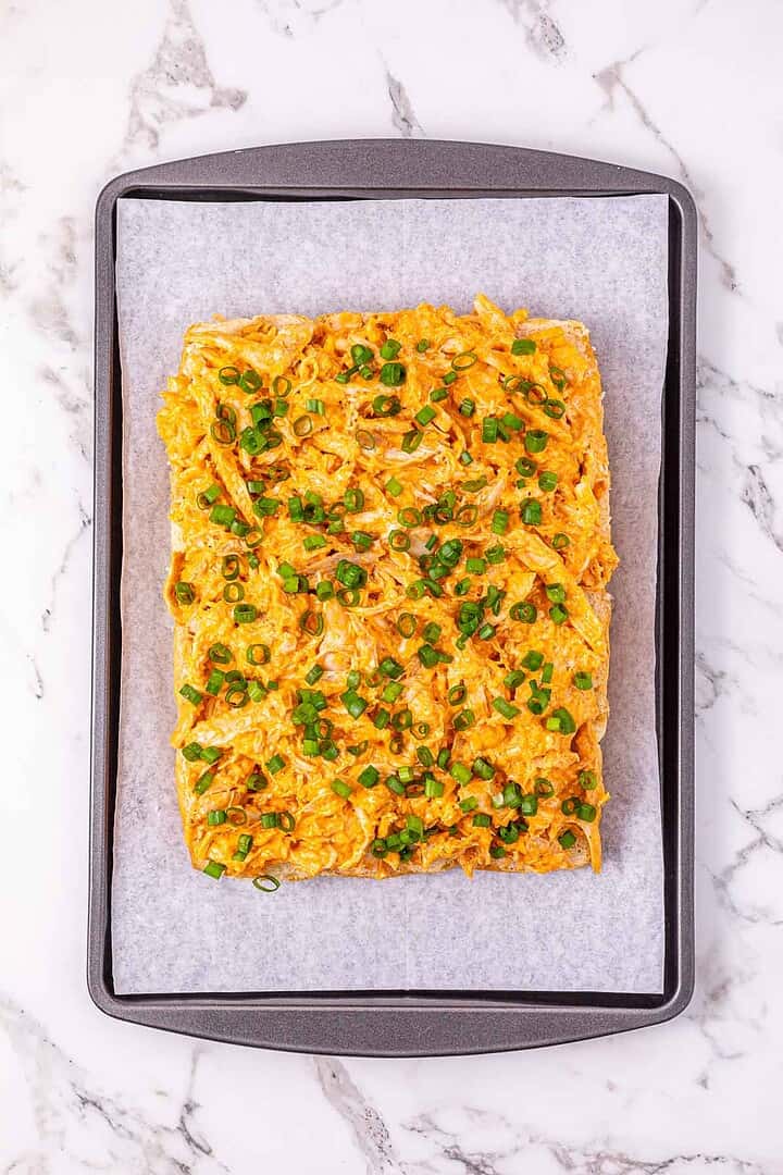 Rectangular flatbread topped with shredded chicken, cheese, and chopped green onions&mdash;this easy Buffalo Chicken Recipe is perfect for making Buffalo Chicken Sliders on a baking tray.