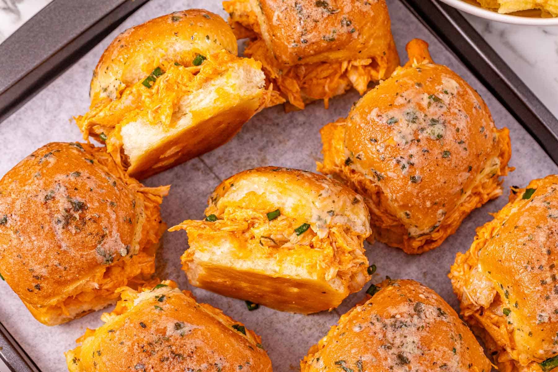 Buffalo Chicken Sliders with shredded chicken and zesty sauce on buttery buns, arranged on a baking tray&mdash;these easy sliders are perfect for game day or any casual gathering.