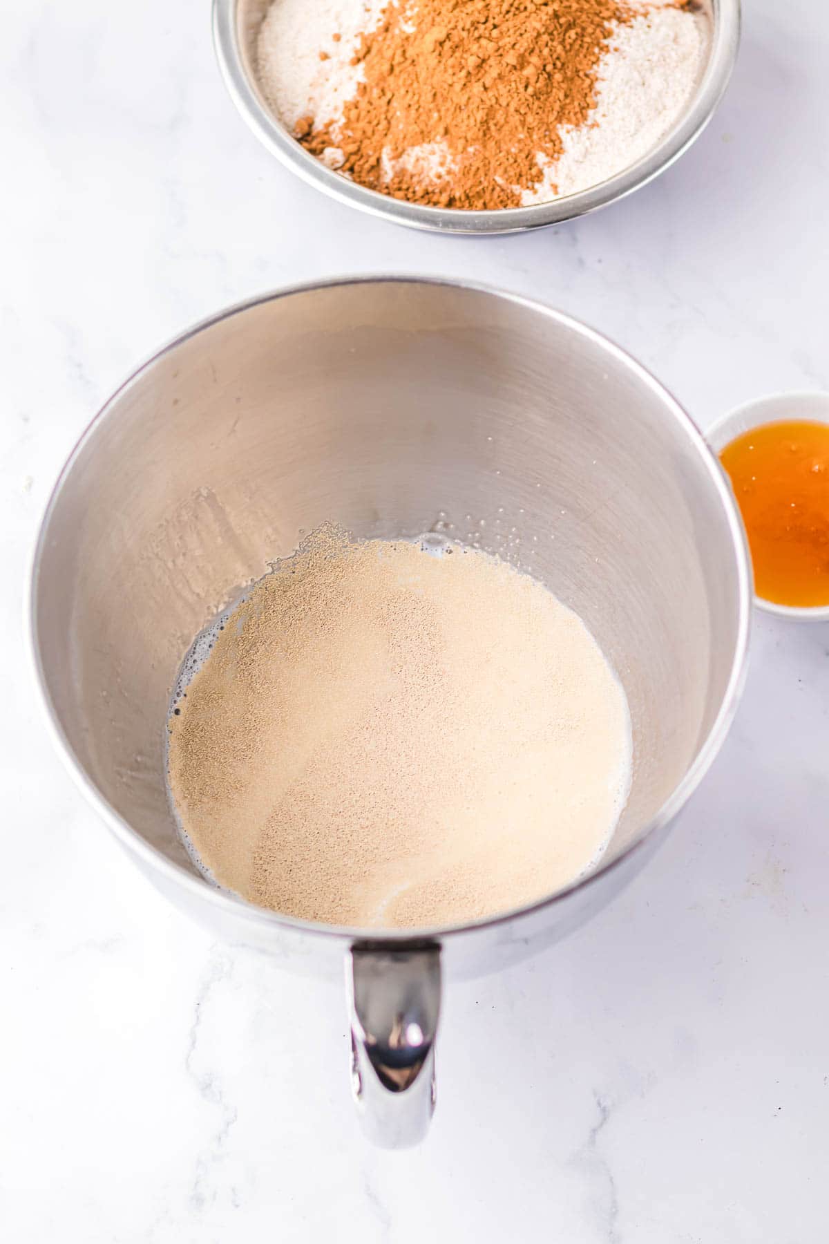 A mixing bowl with yeast dissolving in liquid, alongside flour and cinnamon in a separate bowl—just the start of a Brown Bread recipe inspired by The Cheesecake Factory.