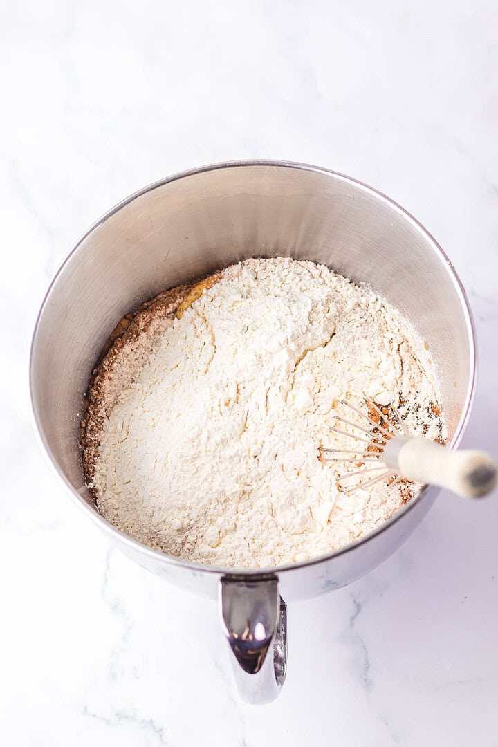 A metal mixing bowl with flour and a whisk on a white marble surface, perfect for crafting a Brown Bread recipe inspired by the Cheesecake Factory.