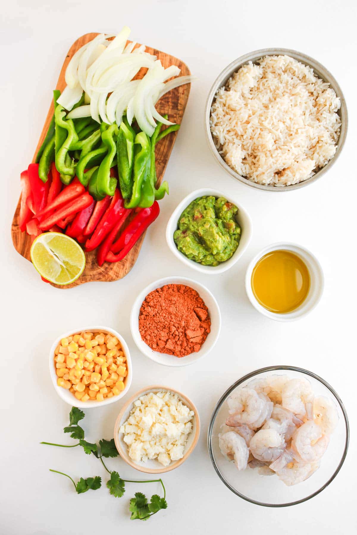 Sliced onions, bell peppers, rice, corn, shrimp, guacamole, cheese, spices, lime, oil, cilantro&mdash;and a drizzle of Chipotle Sauce&mdash;come together for perfect Shrimp Fajita Bowls on your table.