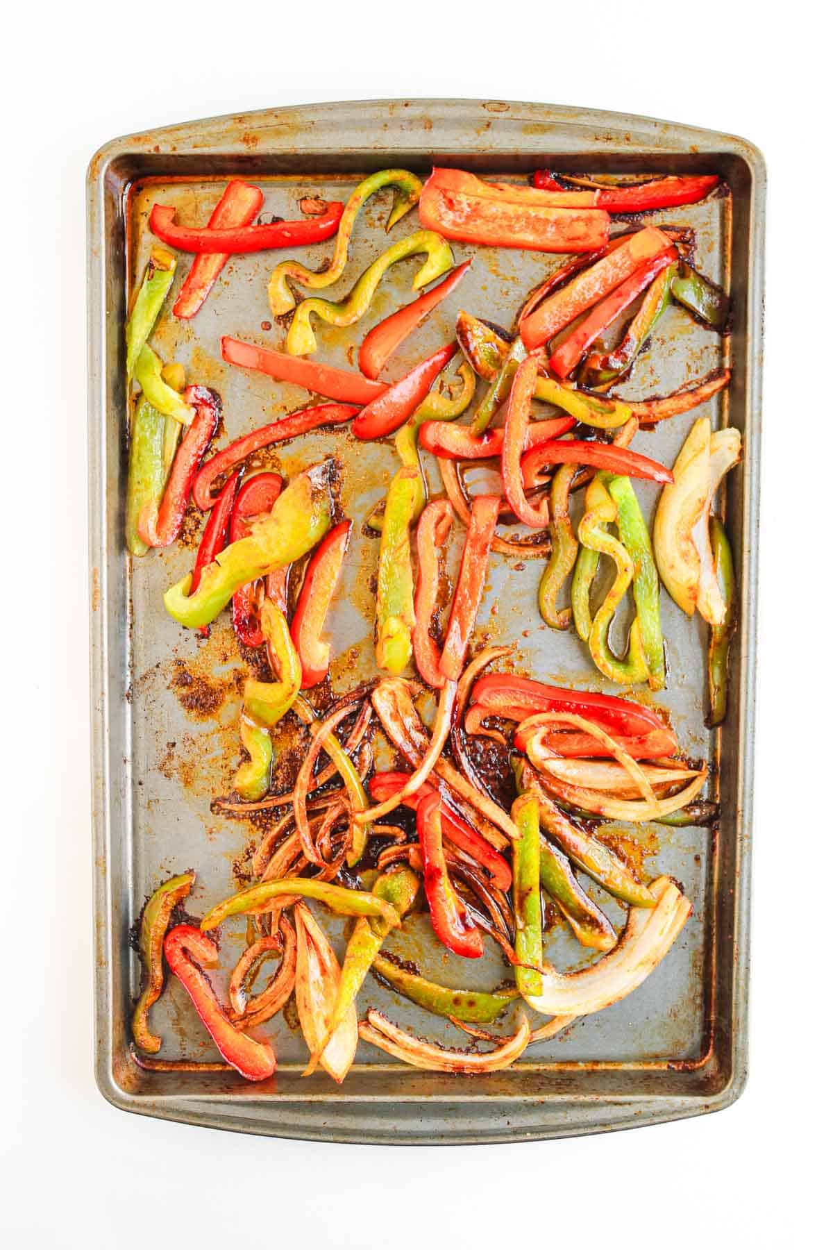 Sliced red, green, and yellow bell peppers and onions roasted on a baking sheet&mdash;perfect for Shrimp Fajita Bowls or Fajita Bowls topped with zesty Chipotle Sauce.