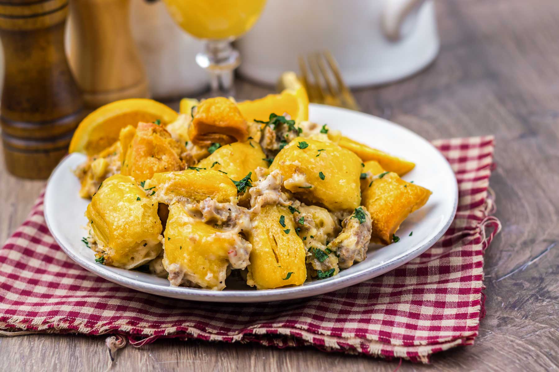 A plate of cheesy baked potatoes with herbs, served on a checkered napkin atop a wooden table—delicious comfort food that could easily be enjoyed alongside a hearty Slow Cooker casserole.
