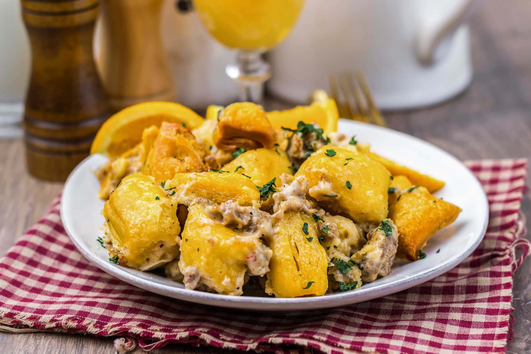 Plate of baked gnocchi casserole with creamy sauce and herbs, served on a red checkered napkin.