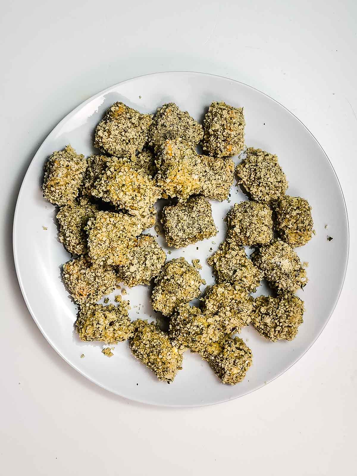 A plate of crispy cheese bites sits on a white surface, perfect for enjoying as a snack straight from the air fryer.