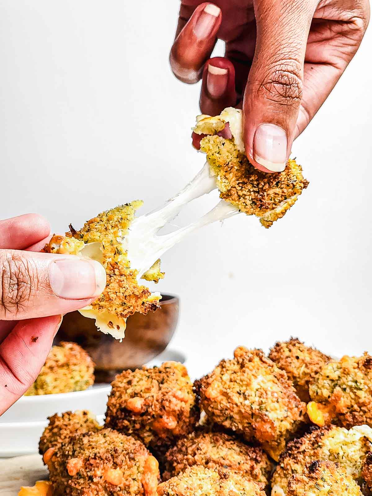 Two hands pull apart crispy Cheese Bites with melted cheese stretching between the pieces, fresh from the Air Fryer.