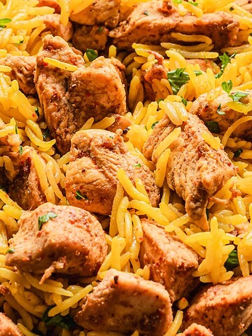 A close-up of spiced yellow rice with chunks of seasoned, cooked chicken.