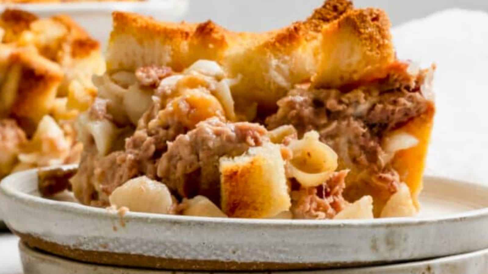 A close-up of a cheesy tuna noodle casserole slice, reminiscent of comforting breakfast casseroles, served on a white plate.