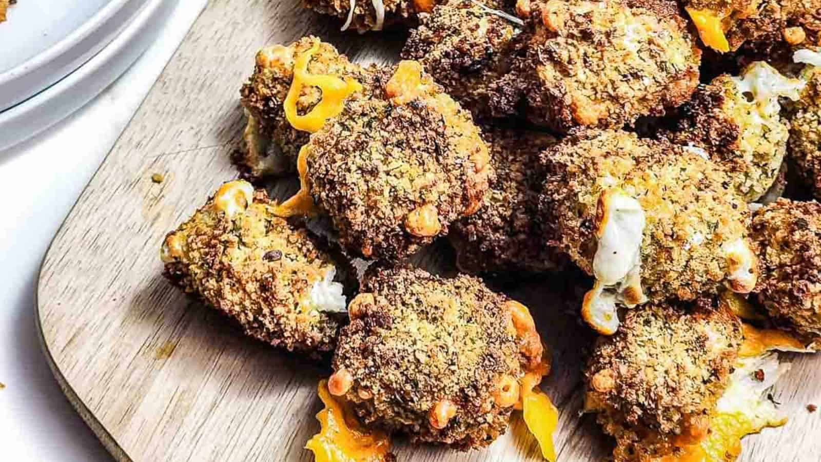 Close-up of crispy, breaded cheese bites with melted cheese on a wooden board.