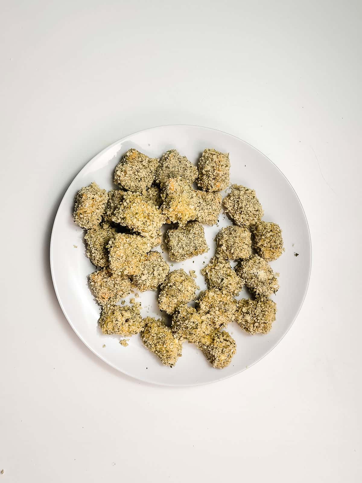 A white plate with several crispy air fryer cheese bites, possibly nuggets, arranged on a white background.