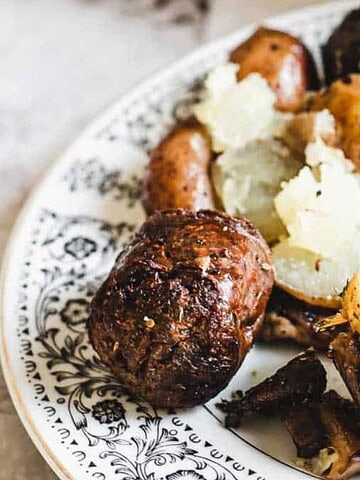 A fork with roasted, seasoned baby potatoes on a decorative plate.