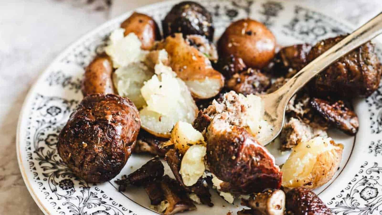 A plate of roasted potatoes with a fork, served on a decorative black and white dish.