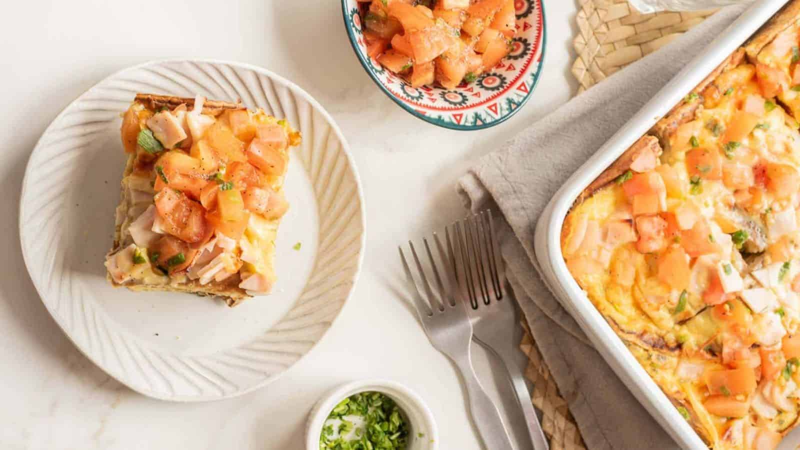 Baked casserole topped with melted cheese and chopped pieces of ham in a white rectangular dish.