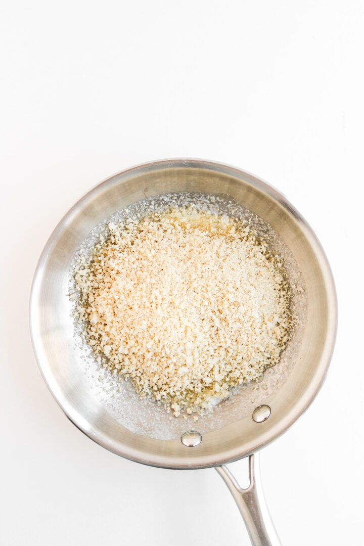 Panko breadcrumbs and melted butter in a stainless steel pan on a white background, perfect for adding crunch to your jalapeno popper loaded cheese fries recipe.