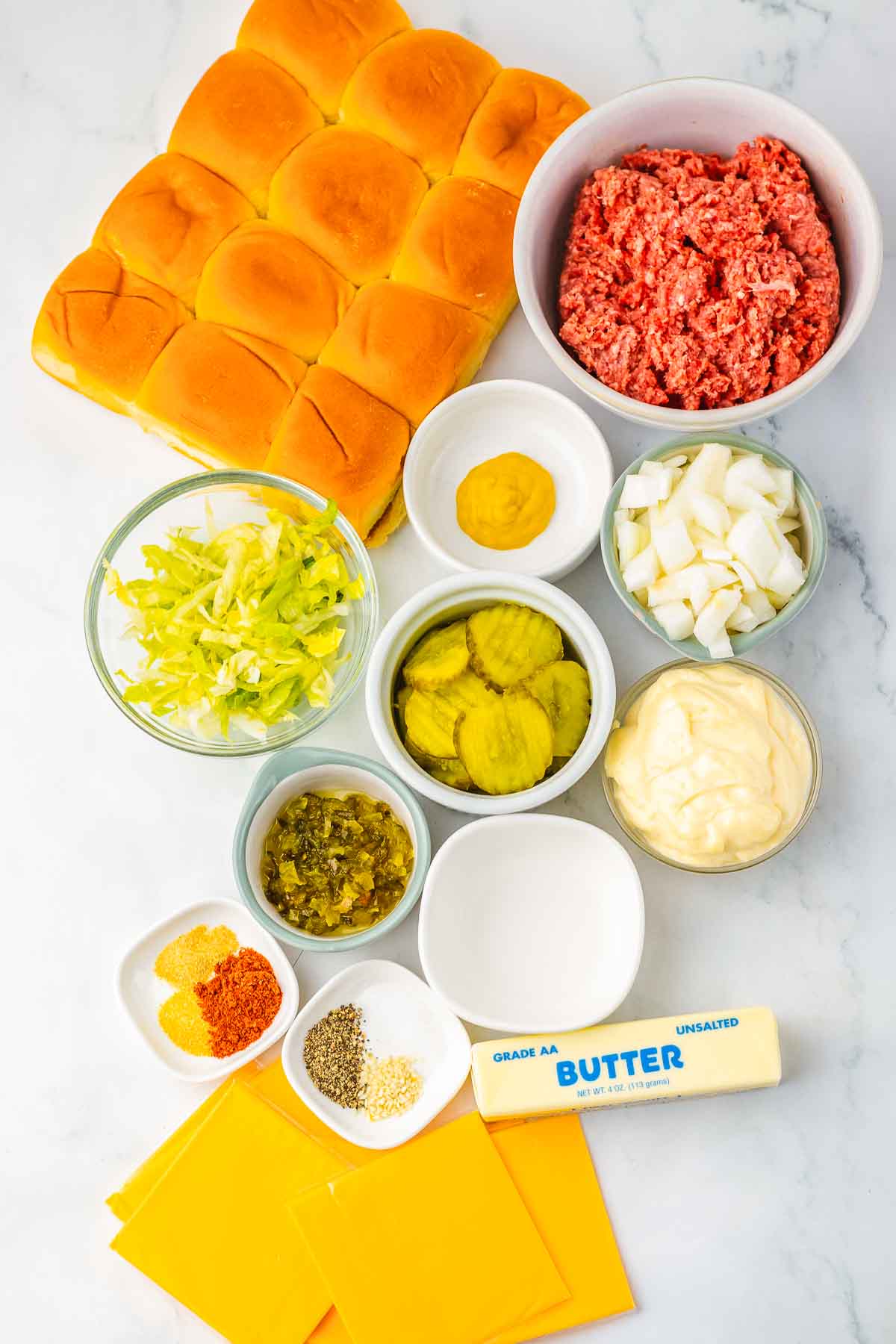 Ingredients for homemade sliders arranged on a counter, including rolls, ground beef, cheese, and condiments&mdash;perfect for making delicious Big Mac Sliders at home.