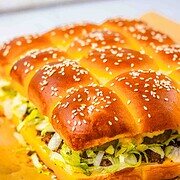 A pull-apart sandwich with sesame buns, lettuce, cheese, and beef on parchment paper—these homemade Big Mac Sliders are perfect for sharing.