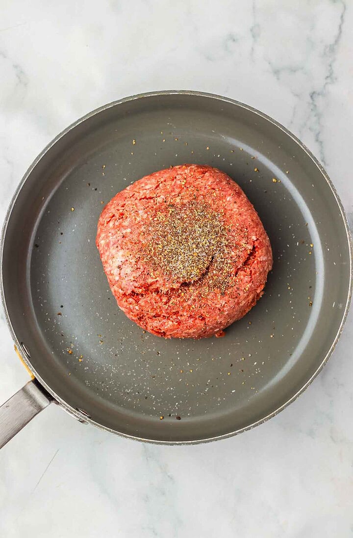 Raw ground beef with seasoning sits in a gray skillet on a marble surface, ready to be transformed into delicious Homemade Sliders or the perfect Big Mac Sliders.