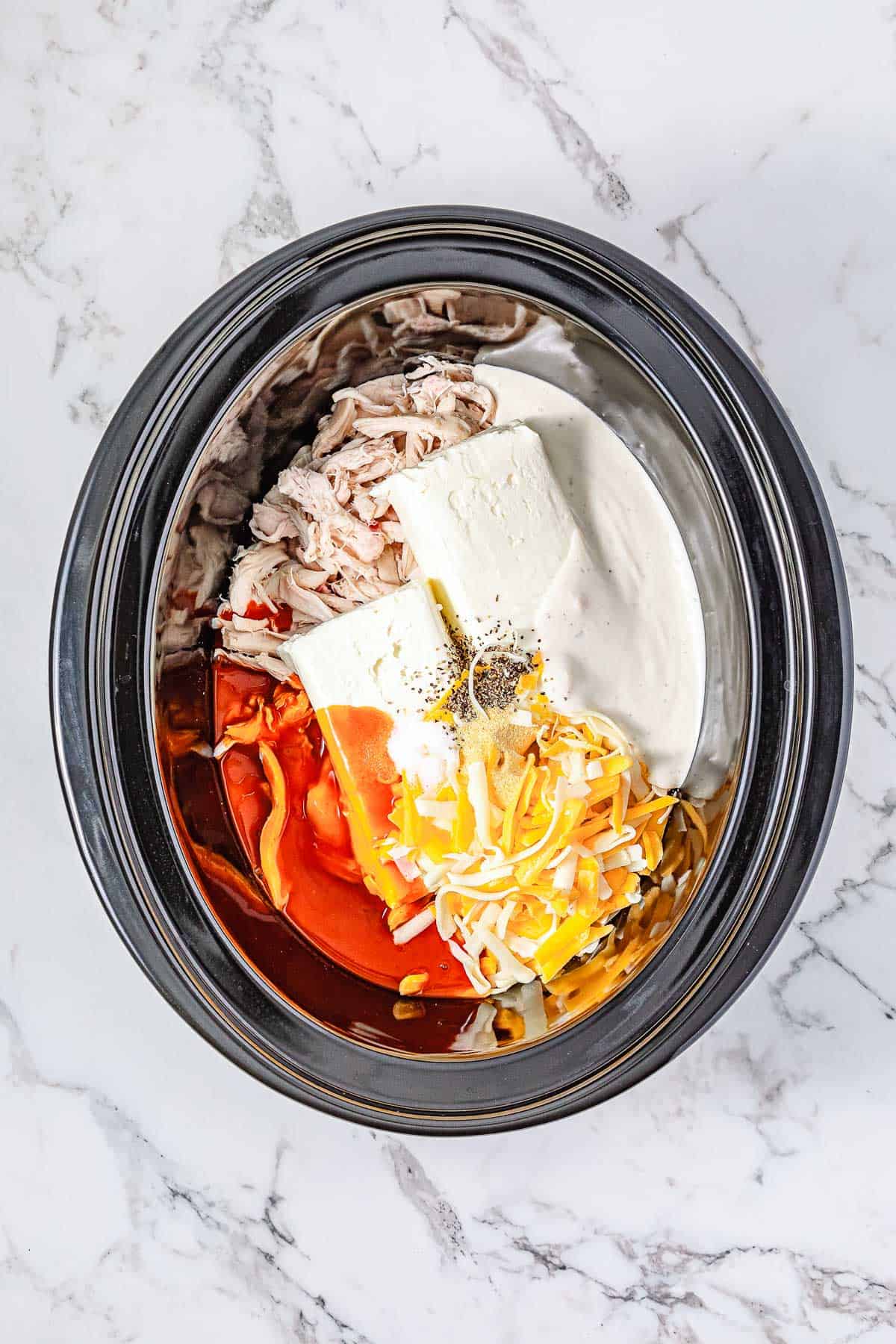 Crockpot filled with shredded chicken, cream cheese, shredded cheese, buffalo sauce, and seasoning makes the perfect Buffalo Chicken Dip for any gathering.