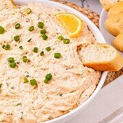 Creamy crab dip topped with chopped green onions and a lemon wedge, served with slices of bread—an easy appetizer recipe perfect for any gathering.