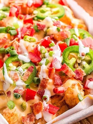 Tater tots topped with cheese sauce, bacon, jalapeños, diced tomatoes, green onions, and ranch dressing.