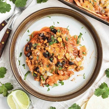 A serving of cheesy Beef Enchilada Casserole with beans and vegetables on a plate, garnished with fresh cilantro.