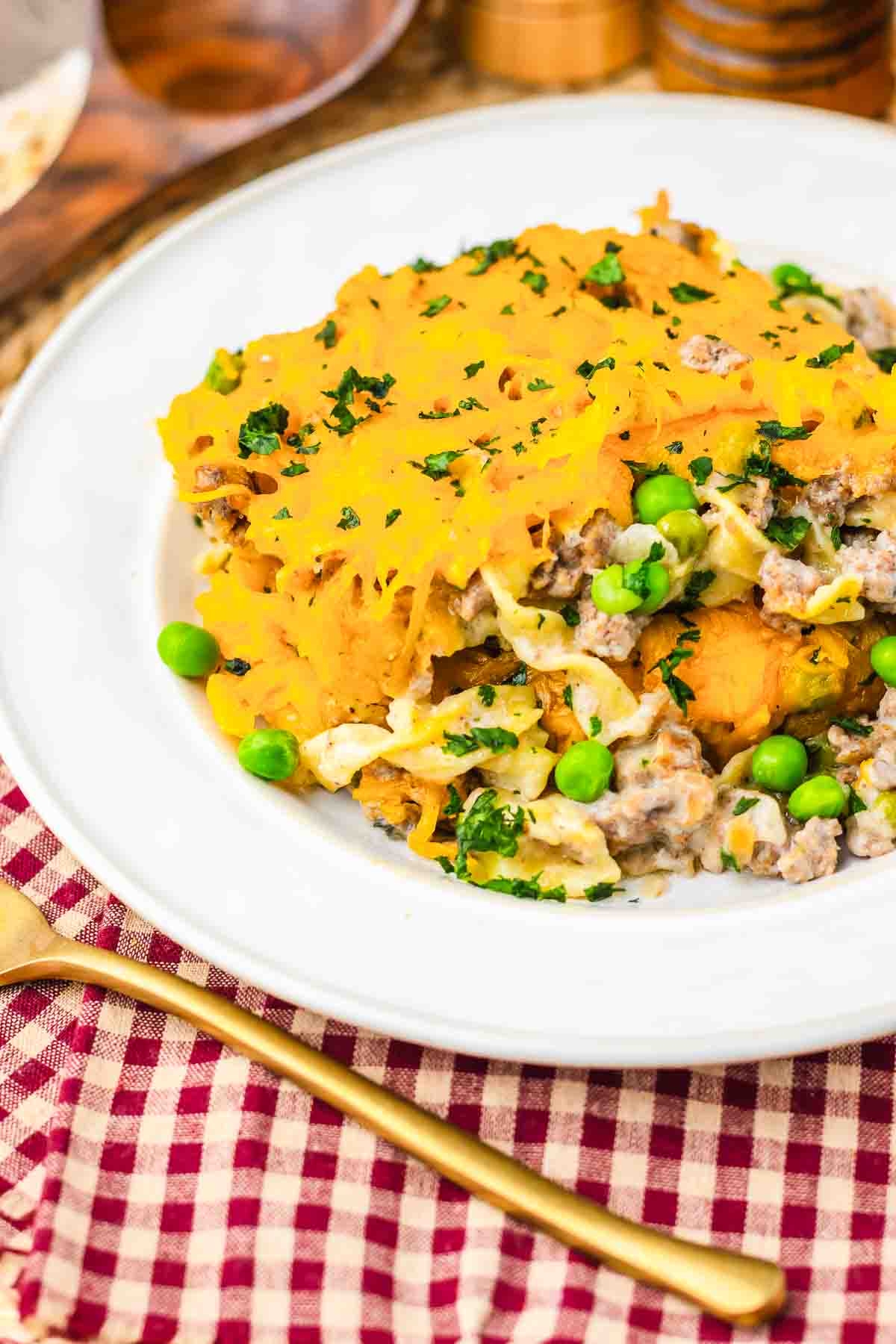 Amish Country Casserole with ground meat, peas, and melted cheese on a white plate, garnished with parsley.