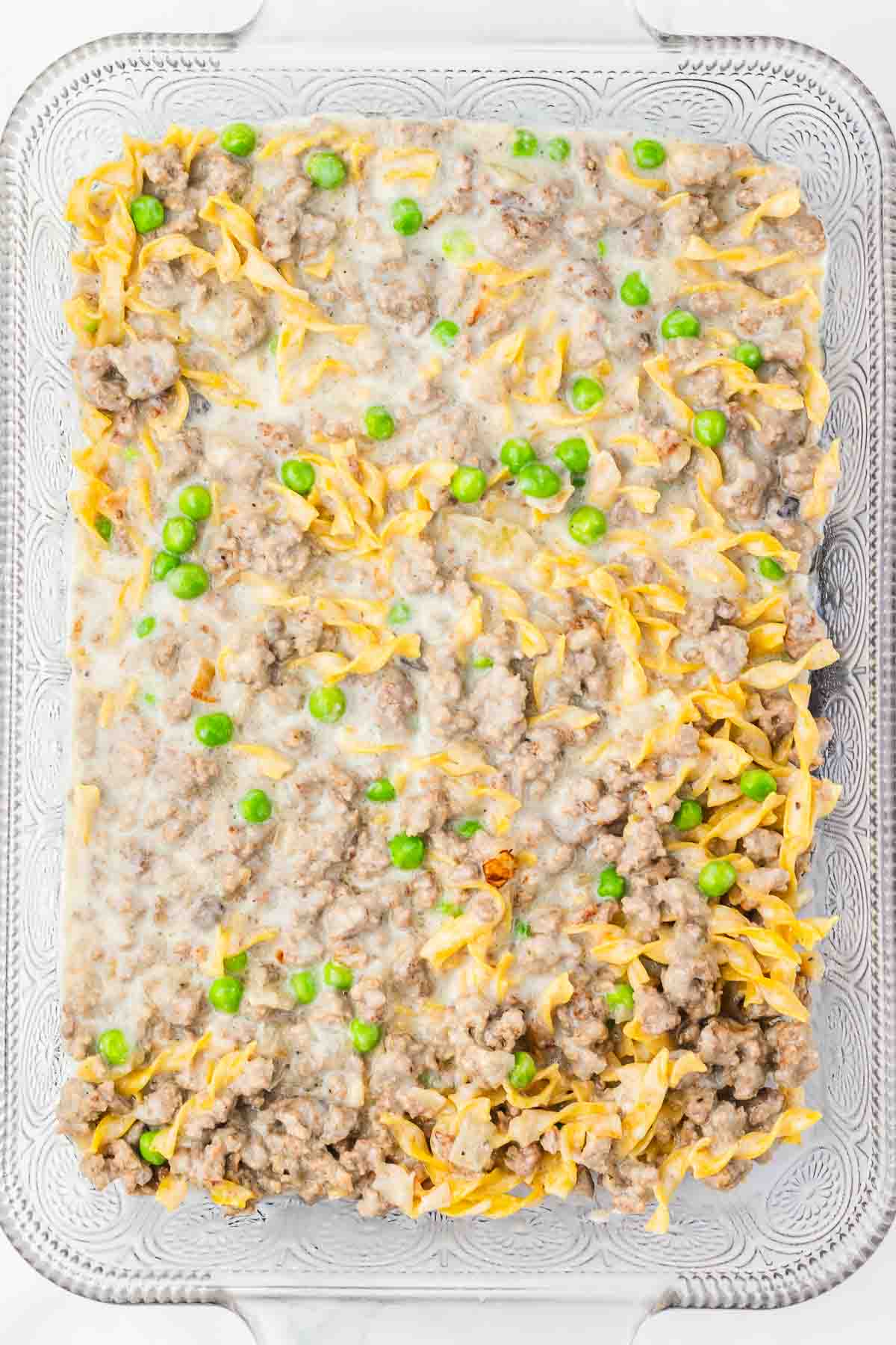Amish Country Casserole with ground meat, noodles, creamy sauce, and green peas baked together in a glass dish.