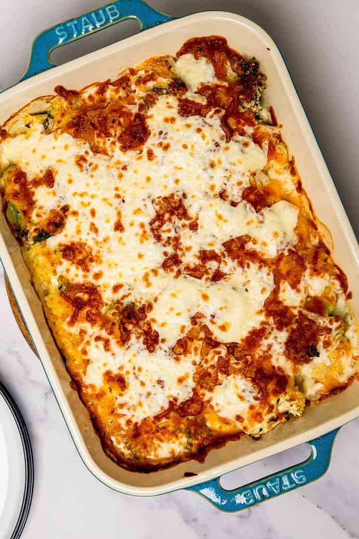 Baked lasagna in a blue Staub dish with melted cheese and golden brown spots on top, reminiscent of a classic cheese casserole.