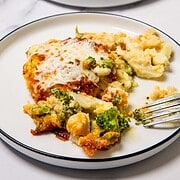 Two plates of cheesy baked macaroni with broccoli and cauliflower, each with a fork and a serving of this comforting cheese casserole recipe.