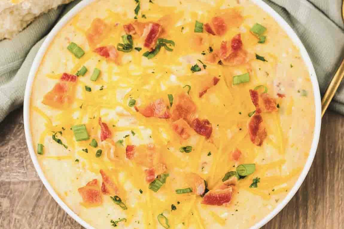 Bowl of creamy Crack Potato Soup topped with shredded cheese, bacon pieces, and chopped green onions.