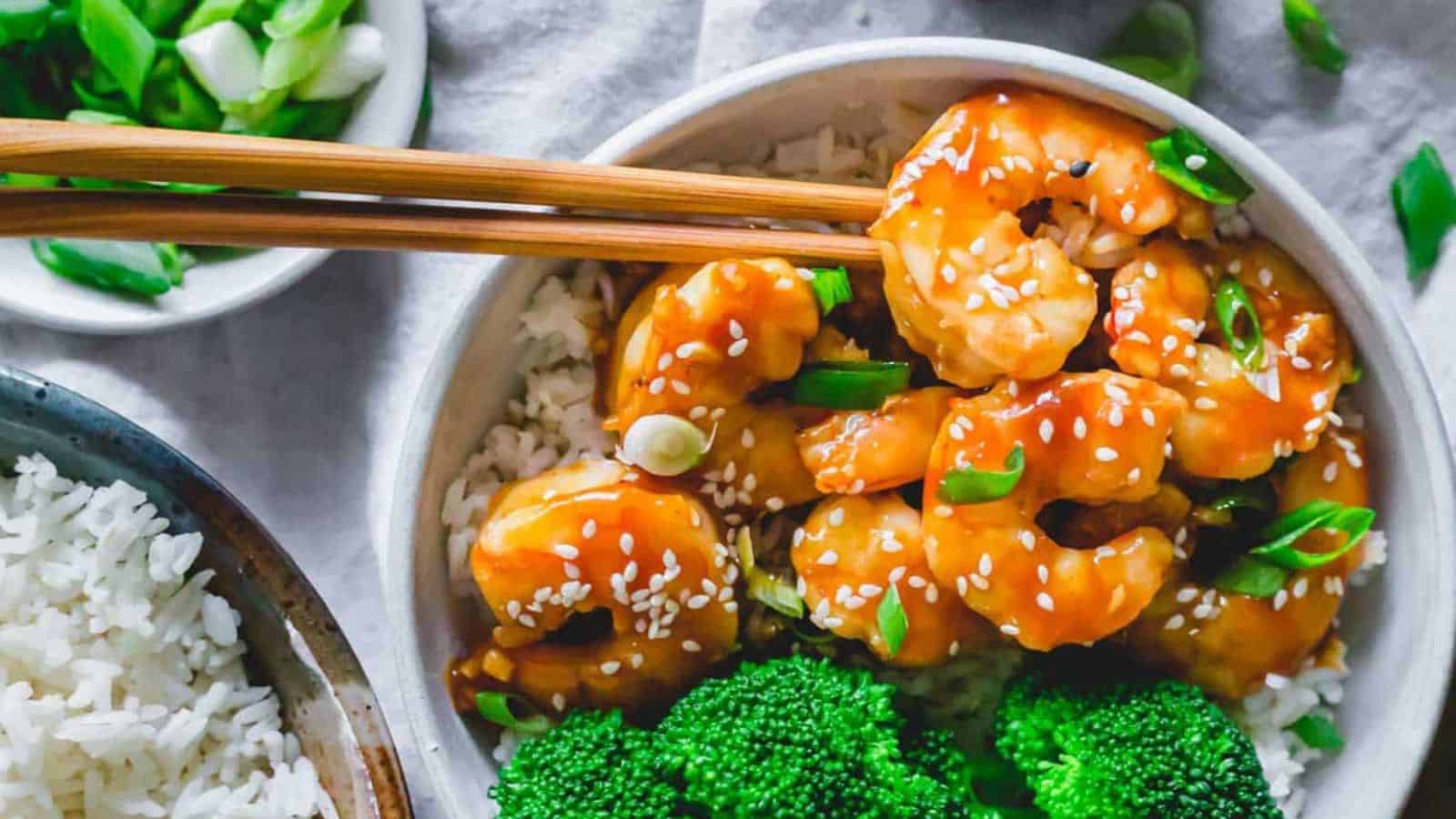 Homemade general tso shrimp with broccoli and rice in a bowl with chopsticks.