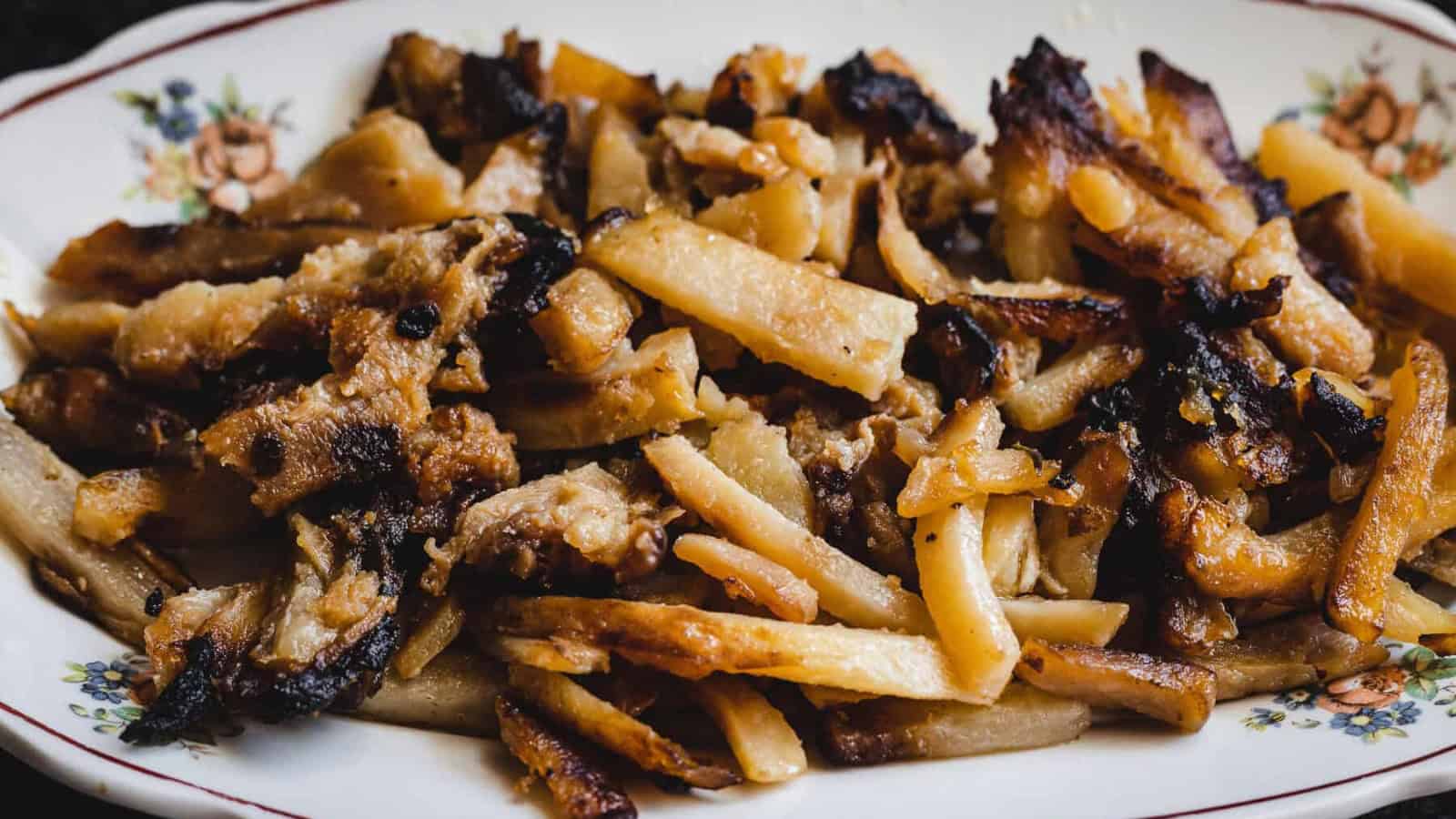 A plate of fried, golden-brown pork trimmings on a floral-patterned dish.
