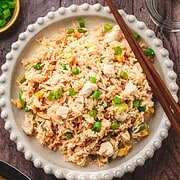A plate of crispy fried rice garnished with green onions, served with chopsticks on a wooden table—a classic recipe perfect for any meal.