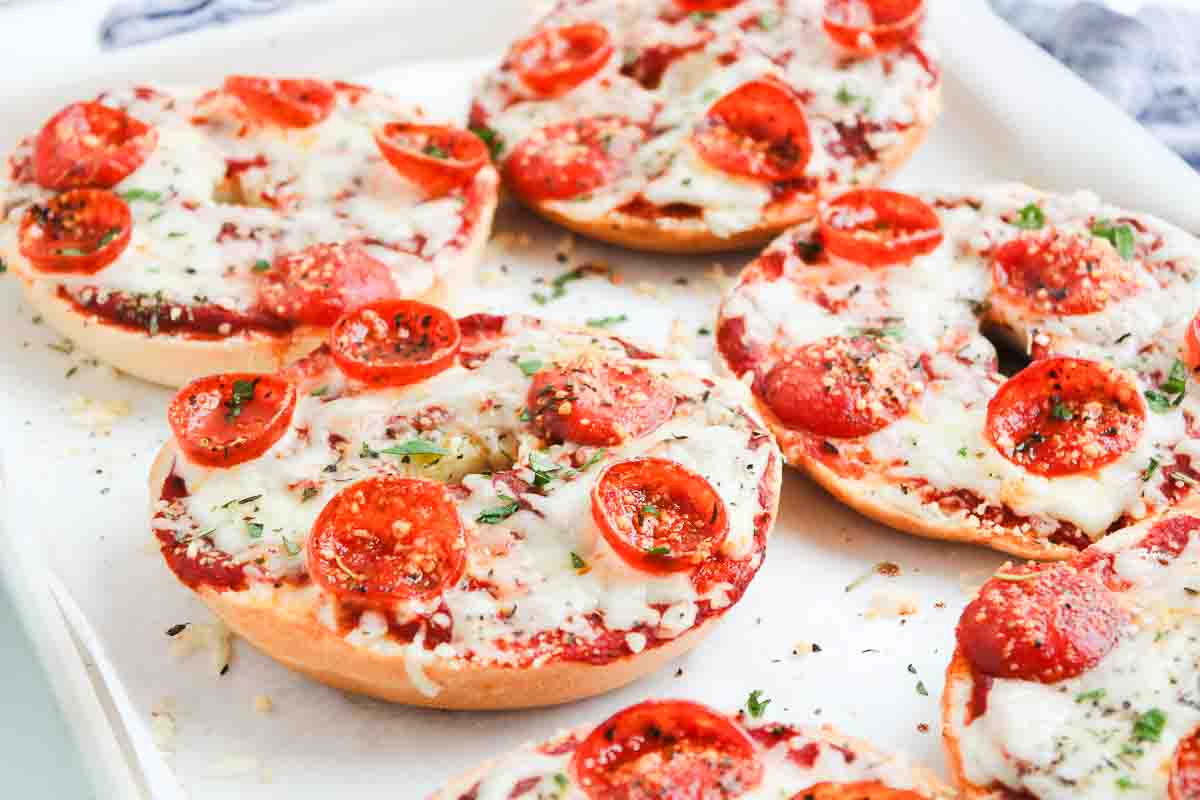 Homemade Pepperoni Pizza Bagels baked to perfection, topped with melted cheese, pepperoni slices, and herbs on a baking tray.