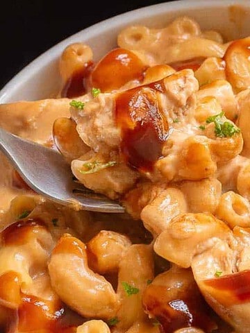 A bowl of creamy macaroni and cheese with pieces of chicken, topped with a drizzle of barbecue sauce—perfect for those seeking quick and delicious air fryer recipes.