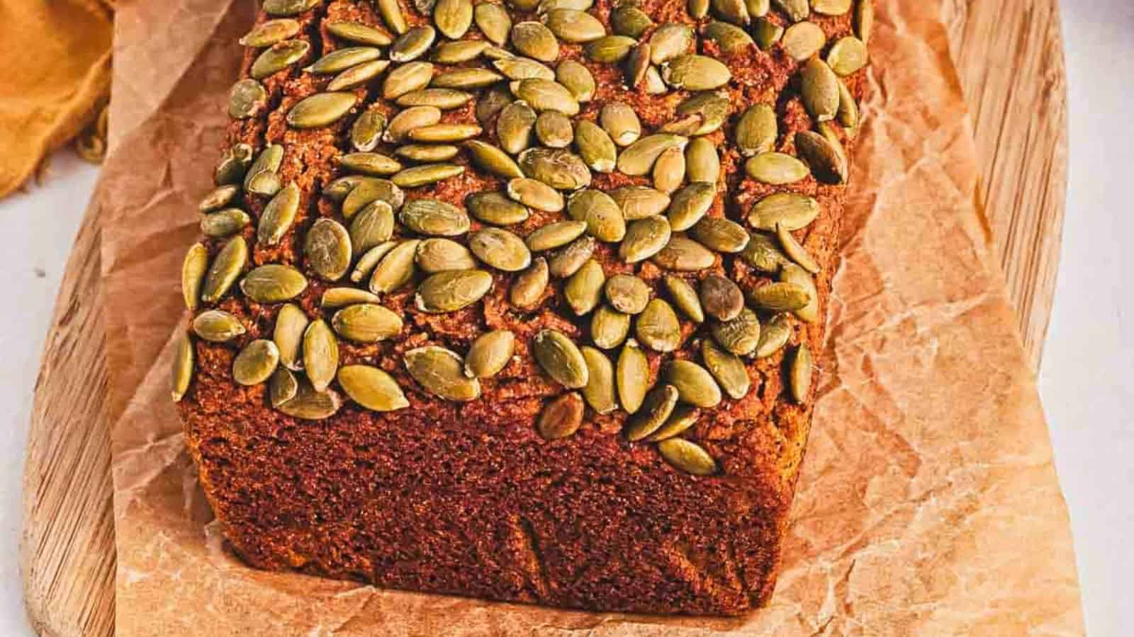 A slice of pumpkin bread on a wooden cutting board.