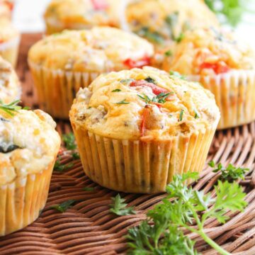 Savory breakfast muffins with herbs and vegetables on a wicker surface, garnished with fresh parsley.