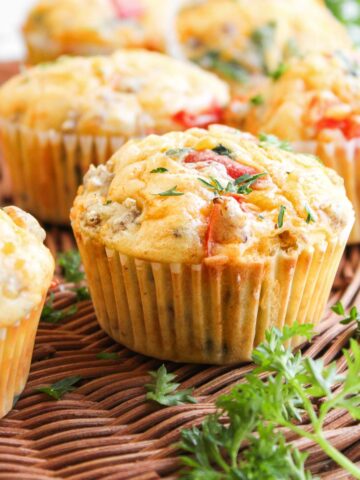 Savory breakfast muffins with herbs and vegetables on a wicker surface, garnished with fresh parsley.