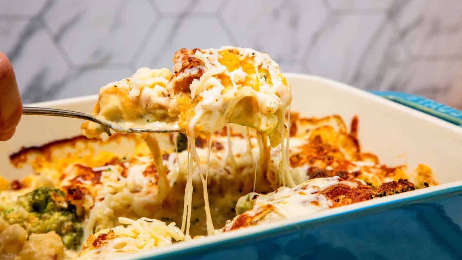 A fork lifting a cheesy, baked casserole from a dish with melted cheese stretching.