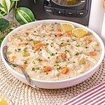 Bowl of creamy turkey and rice soup made with leftover turkey, carrots, celery, and parsley, garnished with lemon wedges.