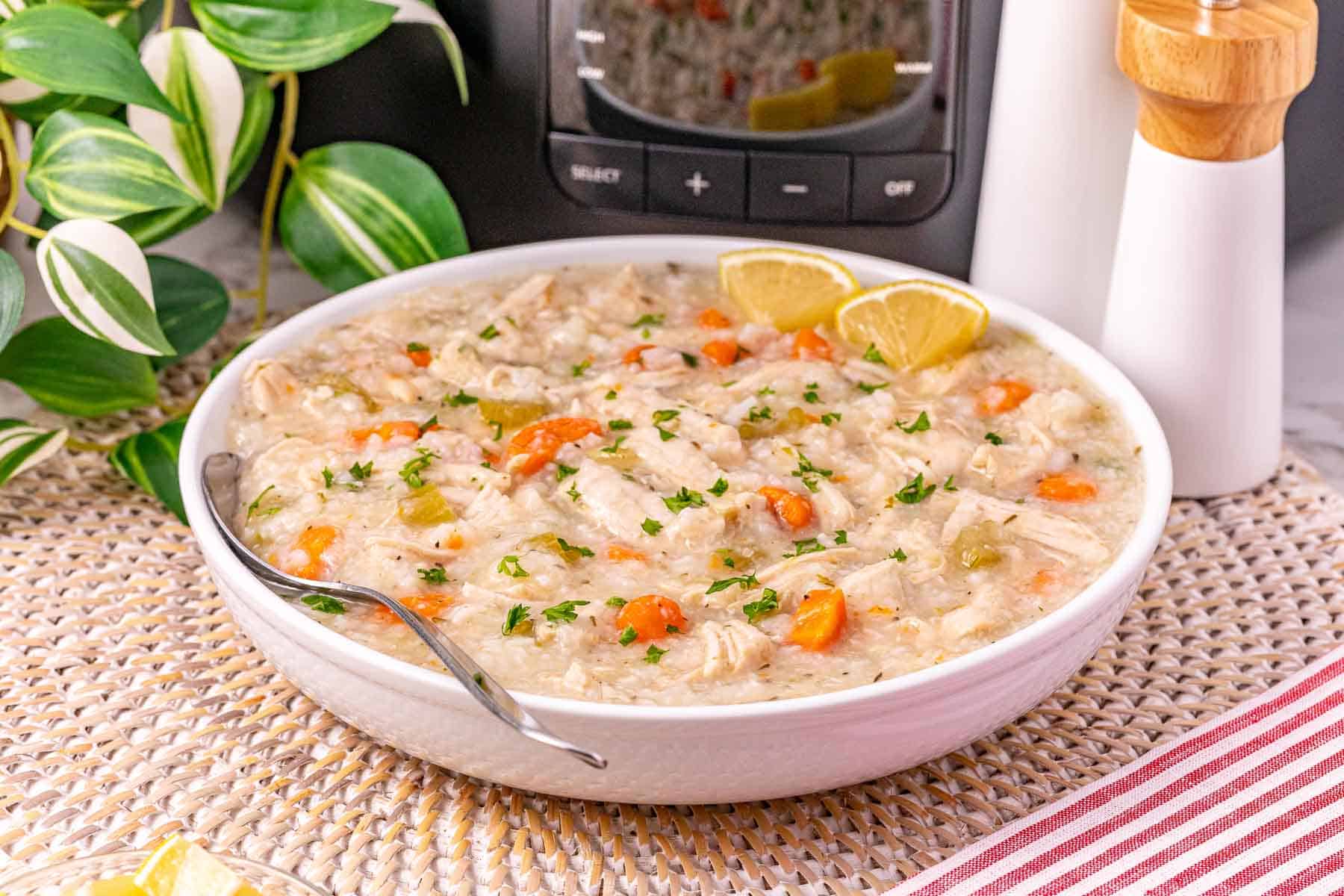 A bowl of creamy turkey and rice soup with carrots, garnished with parsley and lemon wedges—a comforting way to use leftover turkey.