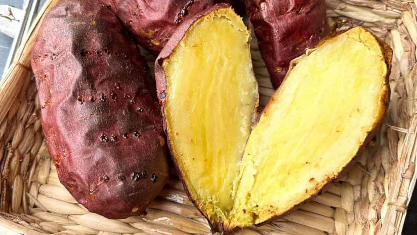 Roasted Japanese sweet potatoes, one cut in half to show the golden, creamy interior, all in a woven basket.