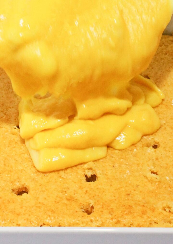 Banana Cream custard is poured onto a poked cake layer in a baking dish, creating a delicious No Egg Poke Cake.