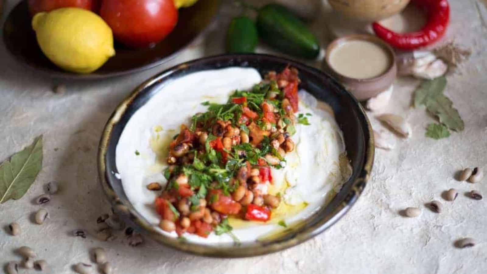 Dip on plate with tomatoes and spicy peppers around.