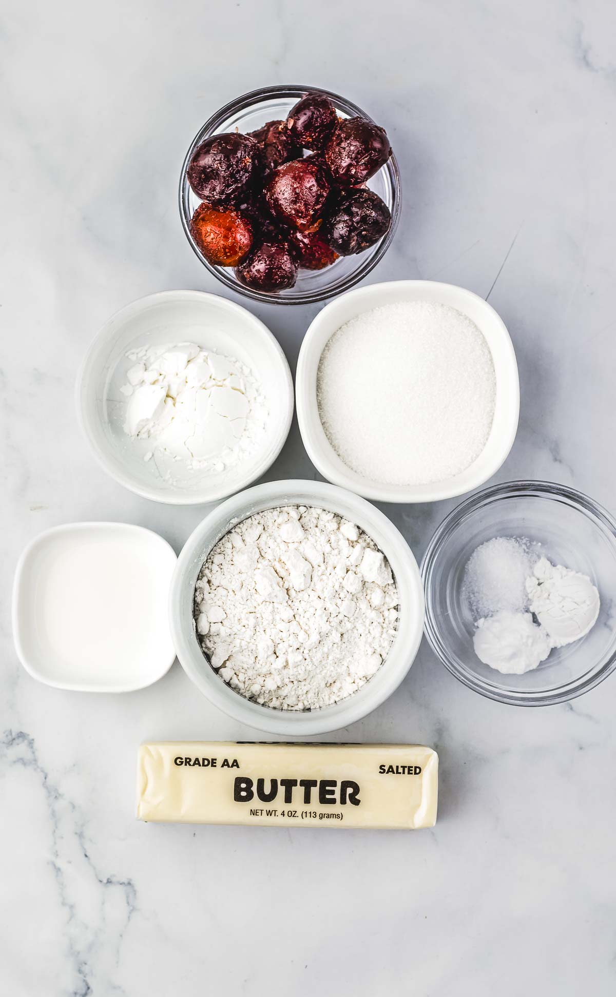 Bowls of cherries, flour, sugar, cornstarch, milk, baking powder, salt, and a stick of salted butter on a counter&mdash;everything you need for a delicious Cherry Pie or Crumb Bars recipe.